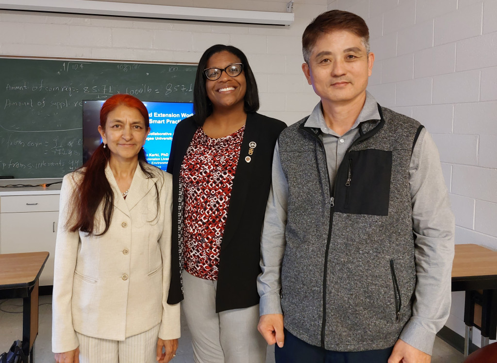 Three Tuskegee University professors stand in a classroom and smile at the camera. 
